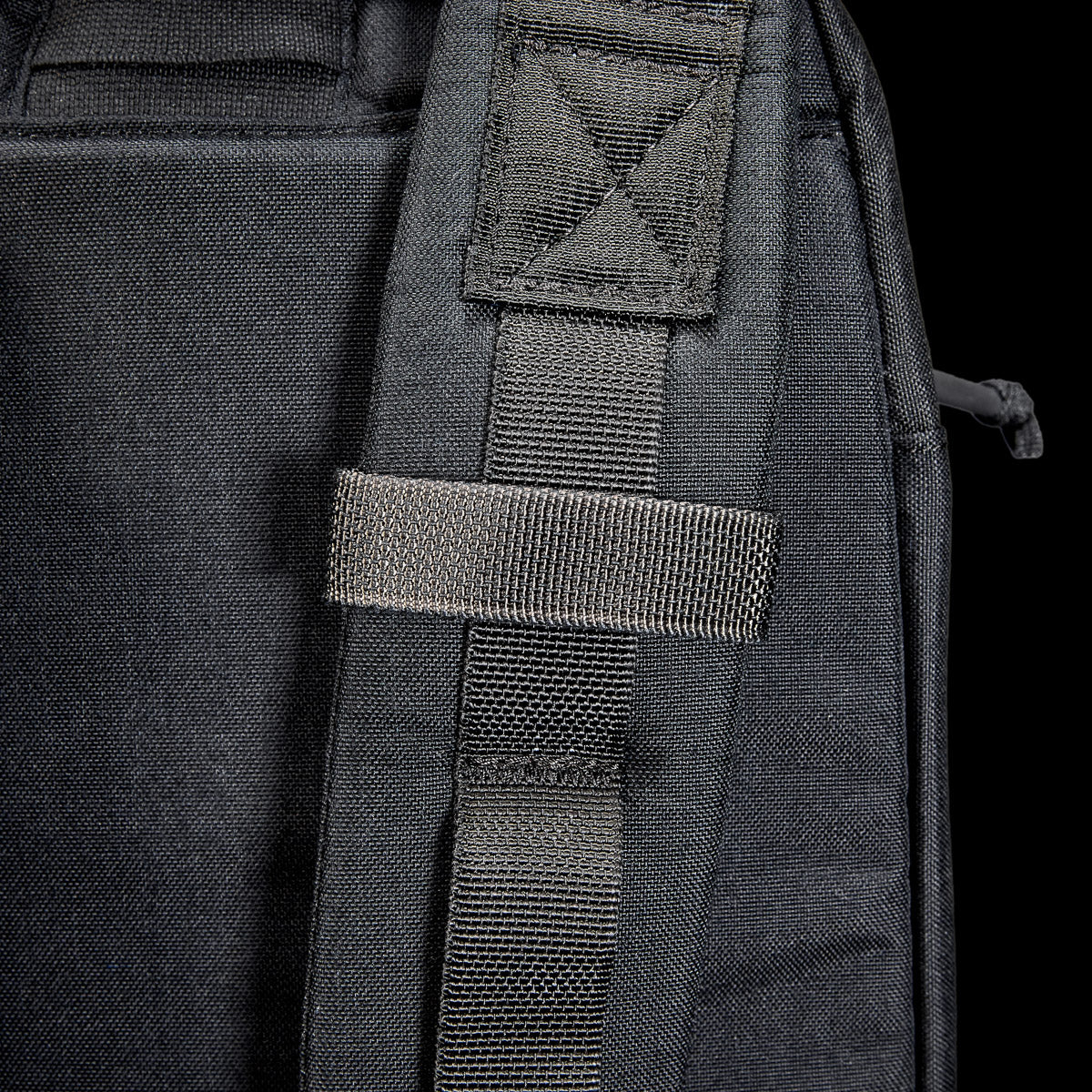 Close-up of the Bullet Ruck USA Throwback's black strap featuring CORDURA construction and a stitched loop, set against a dark background.
