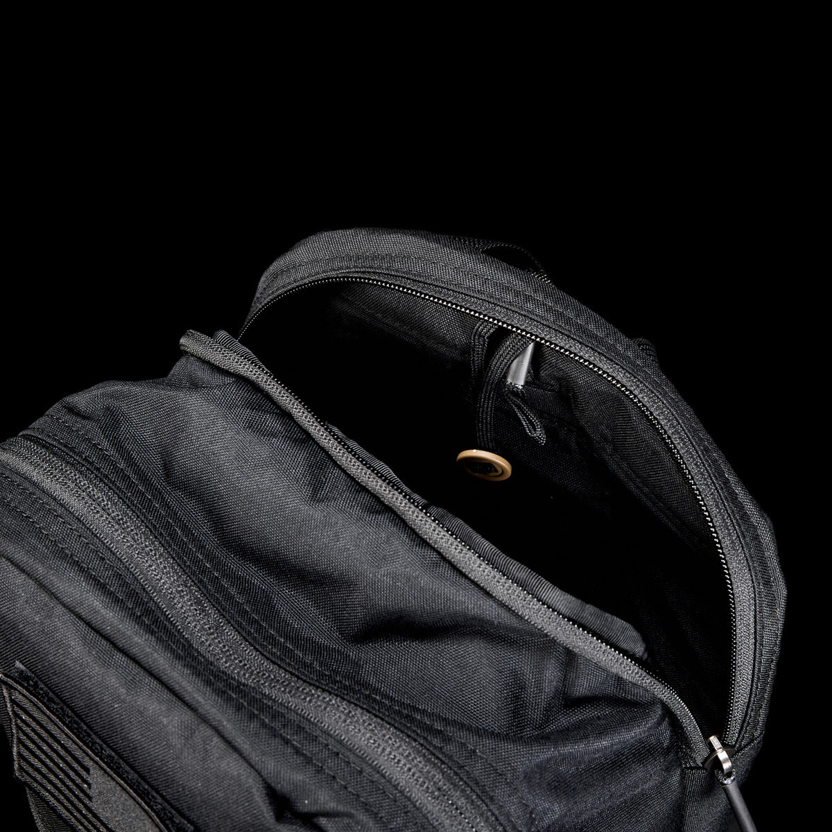 The Bullet Ruck USA Throwback—a black daypack with its main zipper open to reveal a small inner pocket—features durable CORDURA construction for lasting use against a black background.