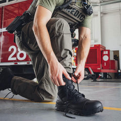 GORUCK medic tying black tactical boots in fire station with rescue truck in background