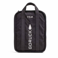A Sand Ruck Plates bag from GORUCK comes in black, featuring two sturdy handles and offering a lifetime guarantee. The design includes "15" in white text with an upward-pointing arrow above the vertically printed GORUCK name. This compact, rectangular bag is ideal for your Rucker adventures