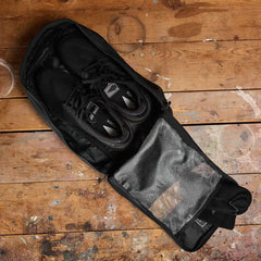 GORUCK gym bag with black athletic shoes and mesh pocket on rustic wooden floor