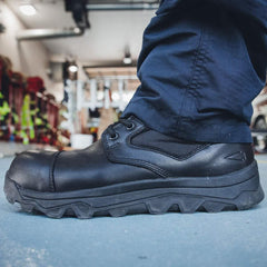 GORUCK rugged black tactical boot on concrete floor, worn by person in navy pants indoors