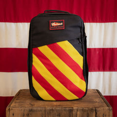 A limited edition Shooter 26L Flash Buffalo Fuzz - Built by Scars sits on a box before a striped flag.