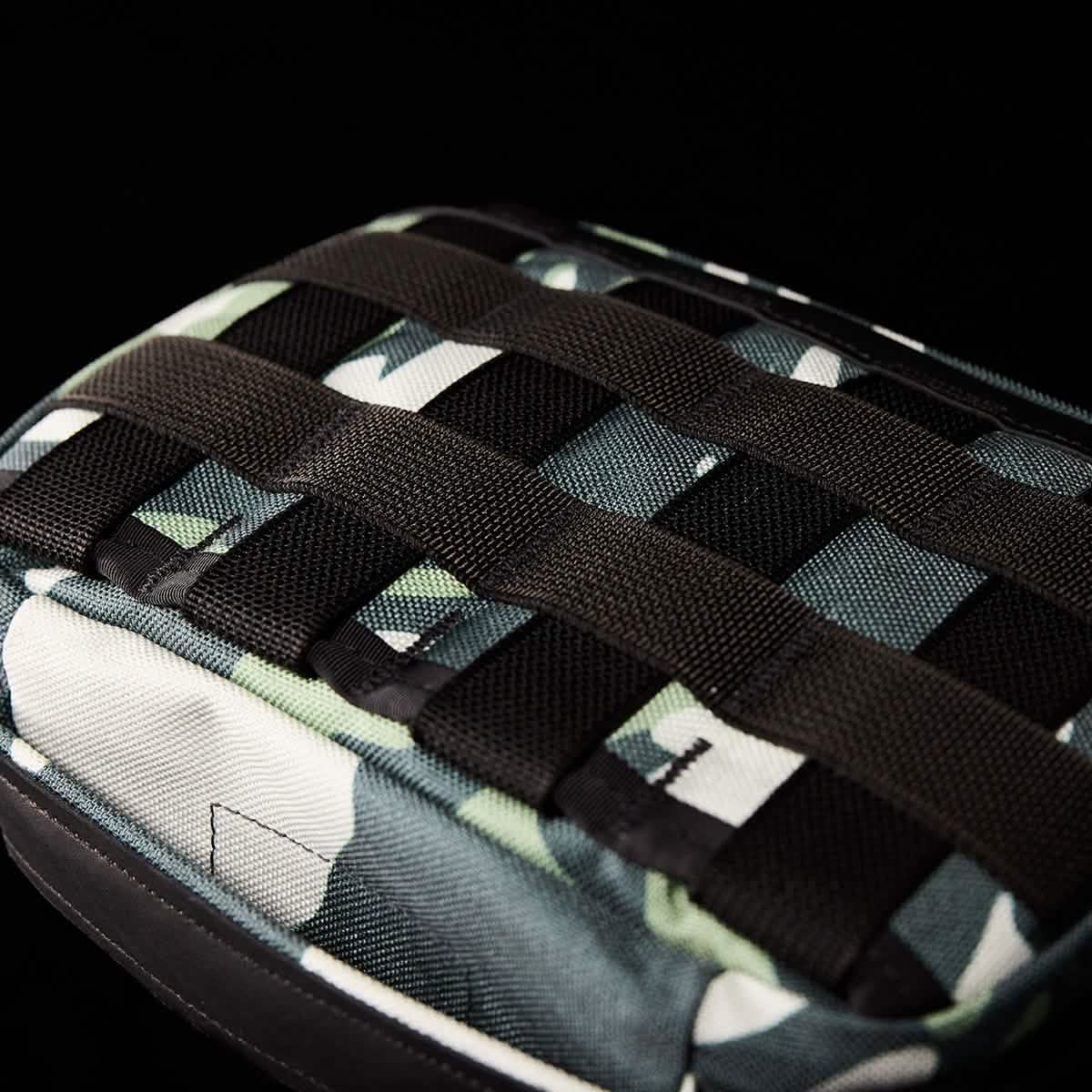 A close-up of the GORUCK GR1 Field Pocket x Gear Patrol, showcasing its black strap grid set against a black background. Its intricate Variegated Elephant Ear Camo design enhances the rugged style of this versatile accessory.
