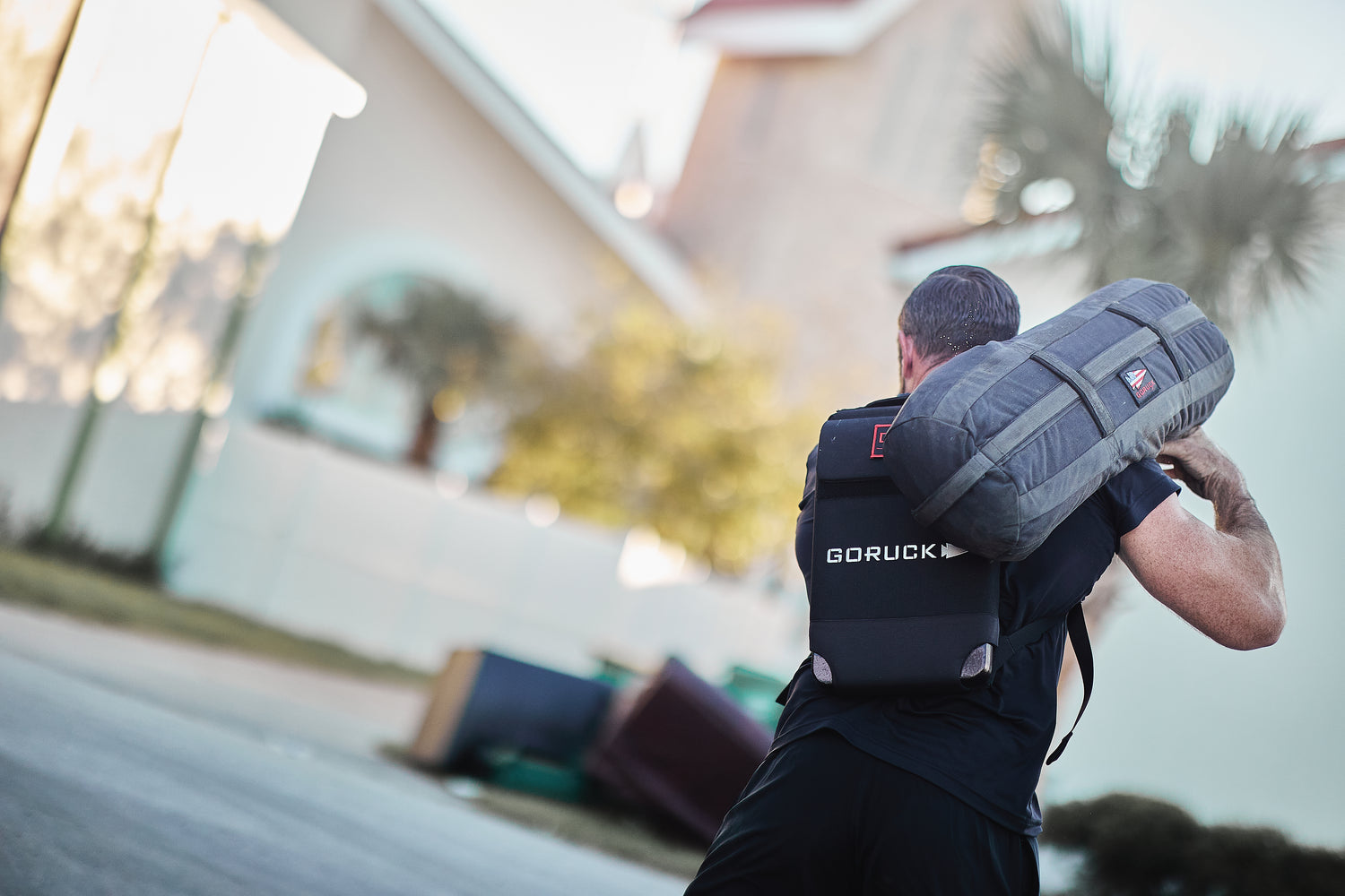 Man carrying a RPC Long + 30LB (Long) Plate Bundle on his shoulder, wearing a backpack with ergonomic lumbar support, walking outdoors.