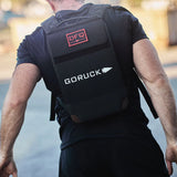 Man wearing GORUCK rucking backpack outdoors, featuring DFQ patch and tough gear design