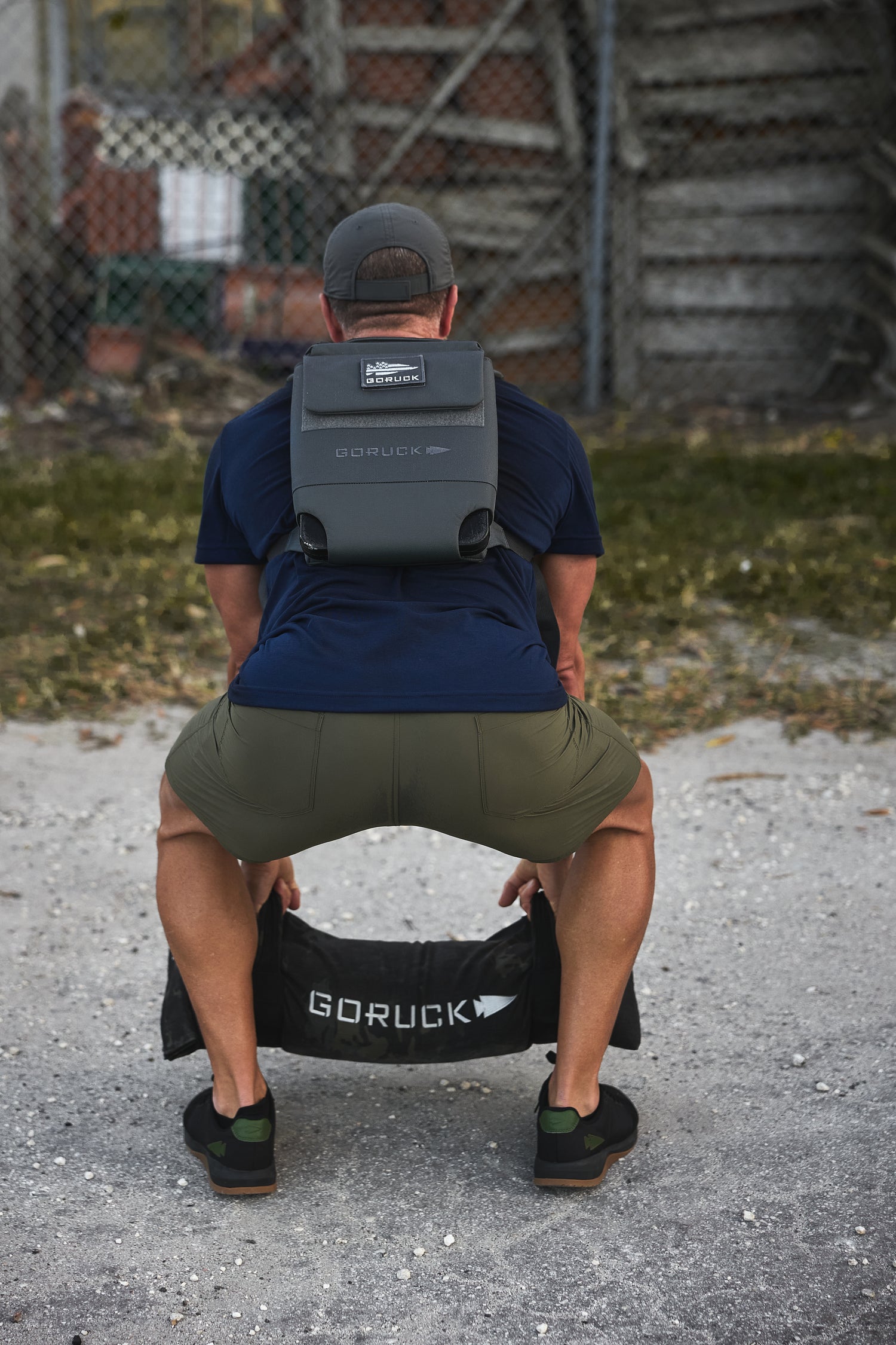 Man squatting outdoors with the RPC 3.0 + 10lb Ruck Sandplate, preparing for weighted training.