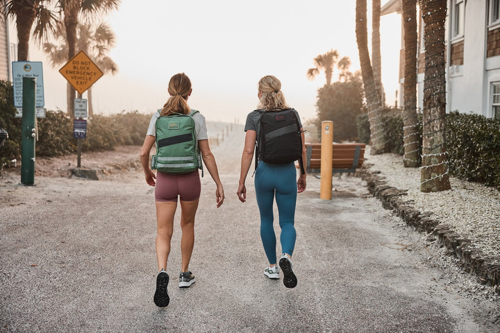 Two people walking away from the camera on a path with backpacks.