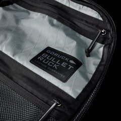 Close-up of gray interior zippered compartments in GORUCK Bullet Ruck with black trim and lifetime guarantee label