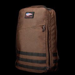 The GR1 is a brown rucksack with black straps and an American flag patch, built to Special Forces standards for everyday carry, displayed against a black background.