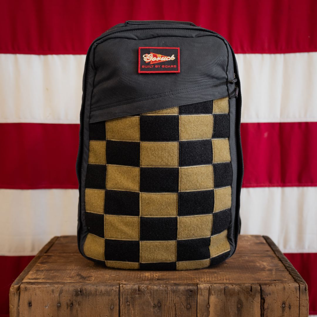 The Checkered GR1 26L - Built by Scars rests on a wooden box with a U.S. flag in the background.