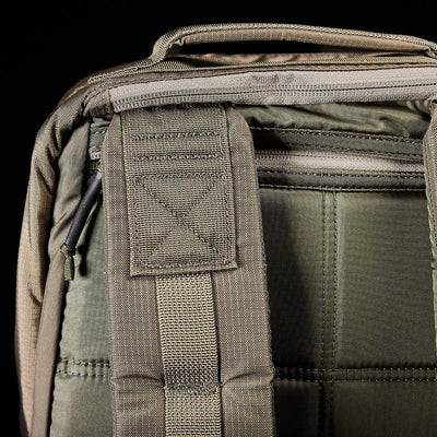 Close-up of a green GORUCK GR1 USA - Ripstop ROBIC® backpack displaying the top handle and back panel. The visible stitching showcases the durable, military-grade fabric and intricate stitched patterns. A zipper is partially visible on the upper section of this water-resistant backpack.