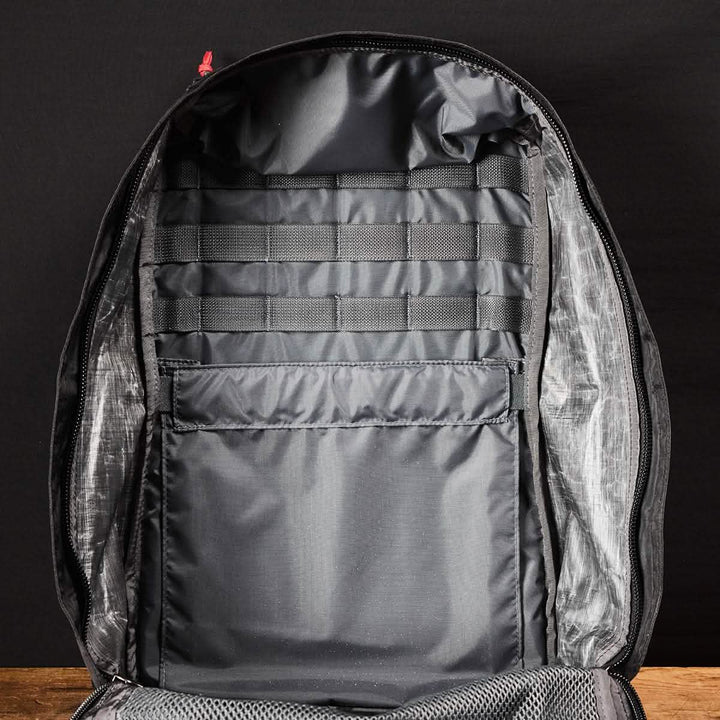 The GR1 USA - Dyneema by GORUCK is displayed against a dark background, revealing an organized interior with multiple compartments and slots for item storage, crafted from durable Dyneema® fabric.