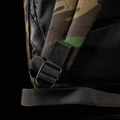 Close-up of the GR1 USA - Heritage Woodland Camo M81 backpack strap with a black adjustment buckle, set against a dark background.