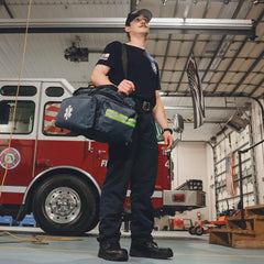 Firefighter with GORUCK rucking bag stands in fire station beside fire truck