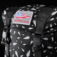 Close-up of GORUCK black rucksack with white arrowhead pattern, USA flag patch, and durable buckle straps