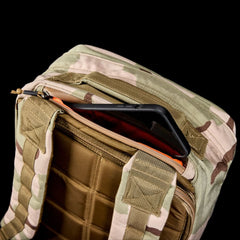 The GR1 USA - Ballistic Nylon Cordura (The Original Ruck) 210D Back Panel in camouflage shows a phone partly visible in its open front pocket, set against a black background—a rugged rucksack inspired by Special Forces.