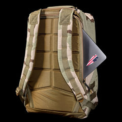 GR1 USA - Ballistic Nylon Cordura (The Original Ruck) with 210D back panel, padded straps, and a laptop peeking from the side pocket—an everyday carry pack inspired by Special Forces, shown on a black background.