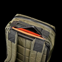 GORUCK dark green tactical backpack with padded straps and partially open top zipper showing orange interior and phone