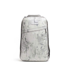 The GR1 is a light gray camo-patterned rucksack with a top handle and diagonal front zipper pocket, inspired by the iconic Special Forces backpack, displayed on a white background.