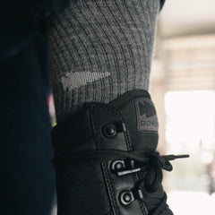 Close-up of GORUCK black rucking boot with gray ribbed sock, outdoor background.