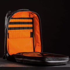 The GR2 USA x Carryology - Ultra Black backpack, made from durable UHMWPE fabric, features a bright orange interior and multiple compartments, shown open against a black background.