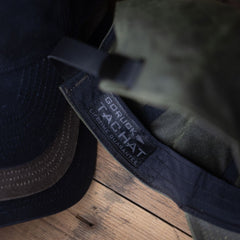 Close-up of a Tac Hat - Heritage with a visible label reading “Lifetime Guarantee” on a wooden surface.
