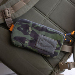 Sternum / Belt Pouch - CORDURA in camouflage, featuring a patch and two zipper pulls, attached to a strap on a green padded surface for hands-free convenience during rucking.