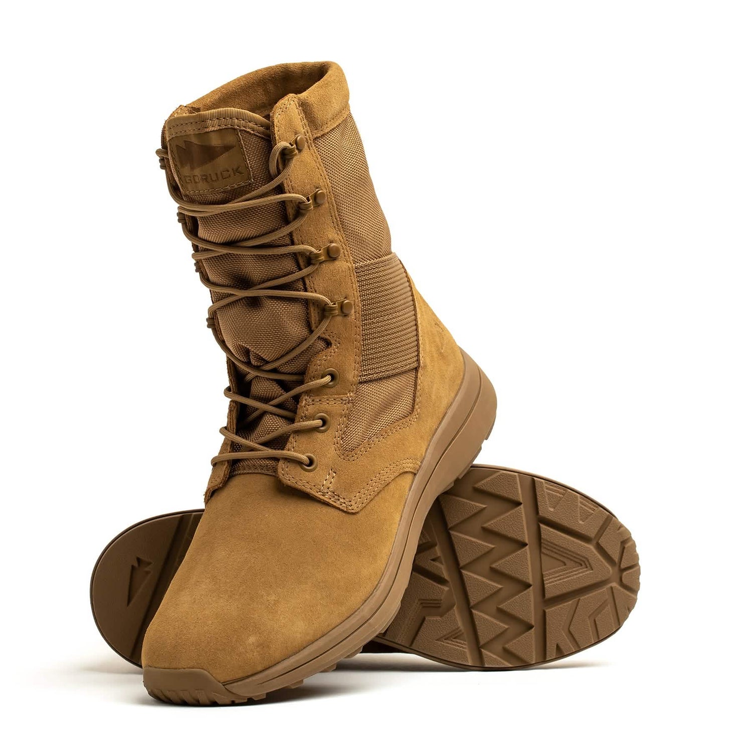 The MACV-1 Hi-Speed - High Top by GORUCK showcases tan military-style features, including high tops, rugged soles, and lace-up fronts. One boot stands upright while the other rests on its side, revealing the tread pattern underneath. Constructed from a combination of suede and nylon, these lightweight rucking boots are perfect for tackling any challenge.