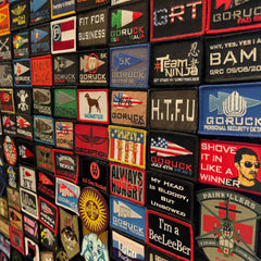 A GORUCK Patch Board covered with colorful embroidered patches featuring various slogans, logos, and designs displayed on Velcro.