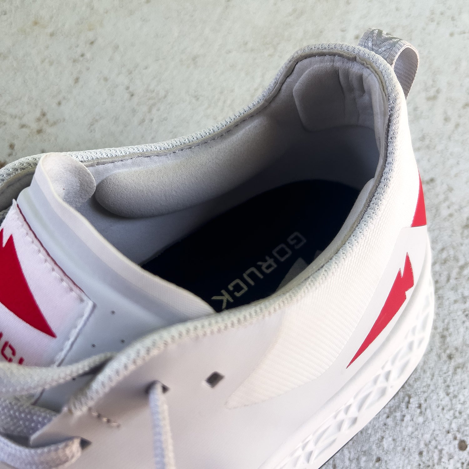 White athletic shoe with red accents, viewed from above, showing the insole labeled 
