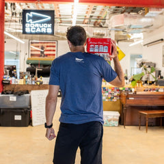 A man in a blue shirt holding an ACRT case on his shoulder stands in a casual, colorful indoor space.