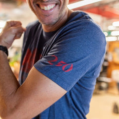 A person smiles and flexes their arm while wearing the Join or Die Tee - Tri-Blend, featuring “270” in red on the blue sleeve—a nod to Ben Franklin’s legacy of colonial unity.