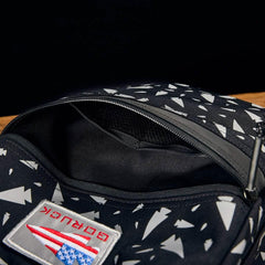 Close-up of a black GORUCK bag with white arrow patterns and partially open zipper showing interior pocket