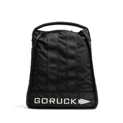 Introducing the Sand Jerry Can by GORUCK: a black backpack featuring a sleek, minimalist design constructed from Special Forces Grade materials. It includes a practical top handle, and the "GORUCK" name along with their signature pointed arrow logo are prominently displayed in white on the bottom front, reflecting its rugged reliability akin to a Jerry Can.