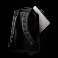 A GR2 USA x Carryology - Ultra Black backpack, crafted from tough UHMWPE fabric, with a gray laptop partially visible inside, set against a black background.