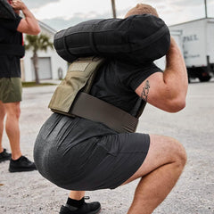 Man performing weighted squat carrying 5lb GORUCK sandbag on shoulders wearing tactical gear outdoors