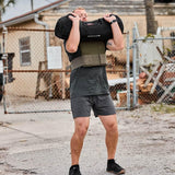 Man in GORUCK gear lifting a sandbag outdoors, demonstrating rucking fitness training.