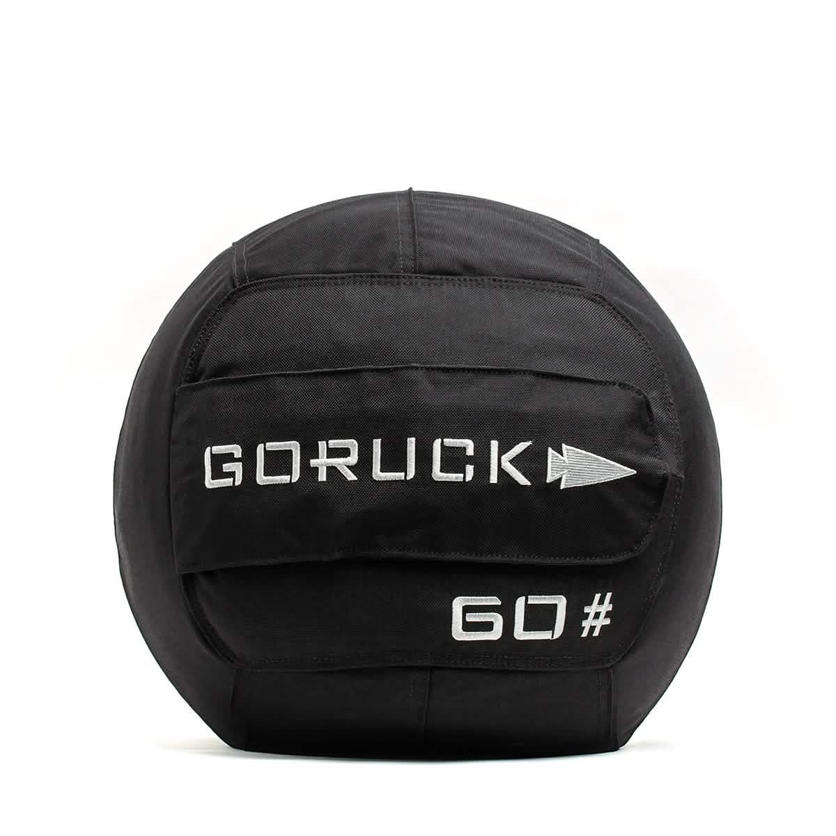 A GORUCK Sand Medicine Ball in black, featuring "10#" printed in white text, is perfect for core stability. It comes with fabric straps for easy handling, making it a great addition to your home gym.