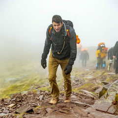 Wearing Merino Compression Socks, a man hikes uphill on a foggy trail, leading a group of hikers behind him.