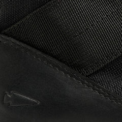 Close-up of black durable nylon webbing and leather detail with stitched arrow logo on GORUCK gear