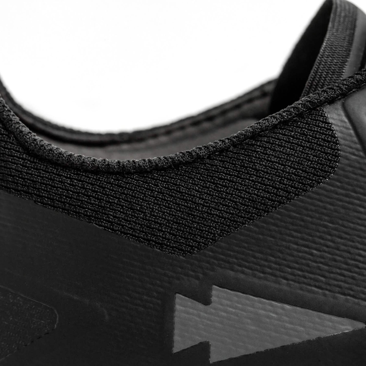 Close-up of the GORUCK Mackall - Black + Forged Iron athletic shoe, perfect for rucking or Special Forces training, emphasizing the textured fabric around the collar and a subtle arrow design on the side. The image showcases the material and stitching details.