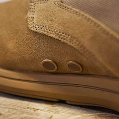 Close-up of the GORUCK MACV-1 Hi-Speed - High Top, a tan suede boot ideal for lightweight rucking. Two small round vents on the side boost breathability. The suede's texture and stitching details are visible as the boot sits on a wooden surface.