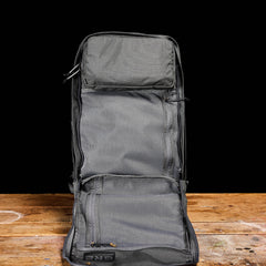 The GR2 - Ballistic Nylon Cordura carry-on travel bag stands upright, open and empty, on a wooden surface with a black background.