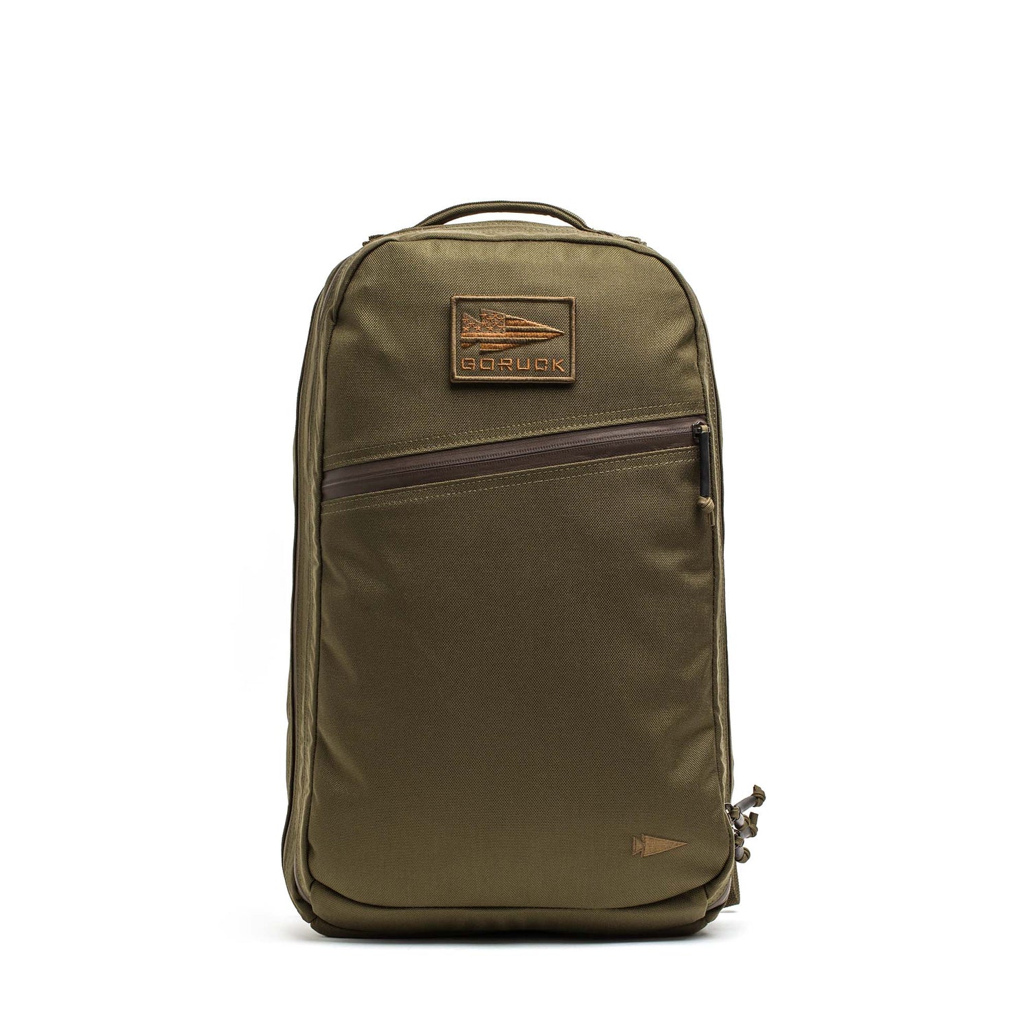 The Double Compartment Bullet Ruck (18L) in ballistic nylon Cordura features an olive green design with a brown leather patch, diagonal front zipper pocket, and bombproof laptop compartment for extra protection.