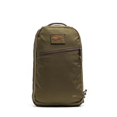 The Double Compartment Bullet Ruck (18L) in ballistic nylon Cordura features an olive green design with a brown leather patch, diagonal front zipper pocket, and bombproof laptop compartment for extra protection.