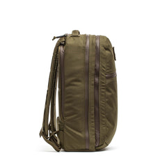 Side view of the Double Compartment Bullet Ruck - Ballistic Nylon Cordura (18L) in olive green with brown zippers, double compartment ruck design, padded shoulder straps, and bombproof laptop compartment on white background.
