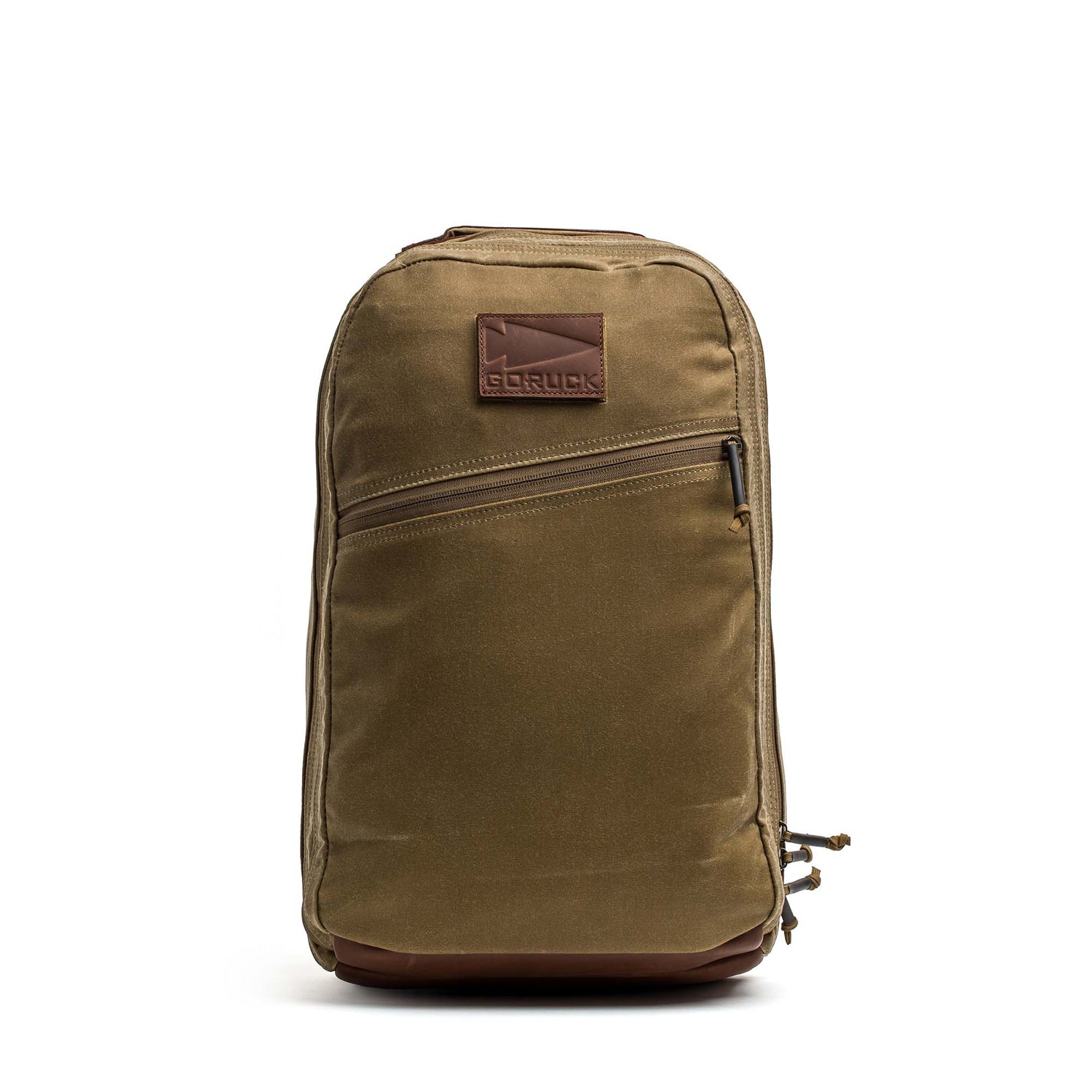 The Double Compartment Bullet Ruck - Heritage Waxed Canvas - 18L features a tan waxed canvas build, front zipper pocket, and a brown leather patch logo—ideal for use as a durable travel daypack.