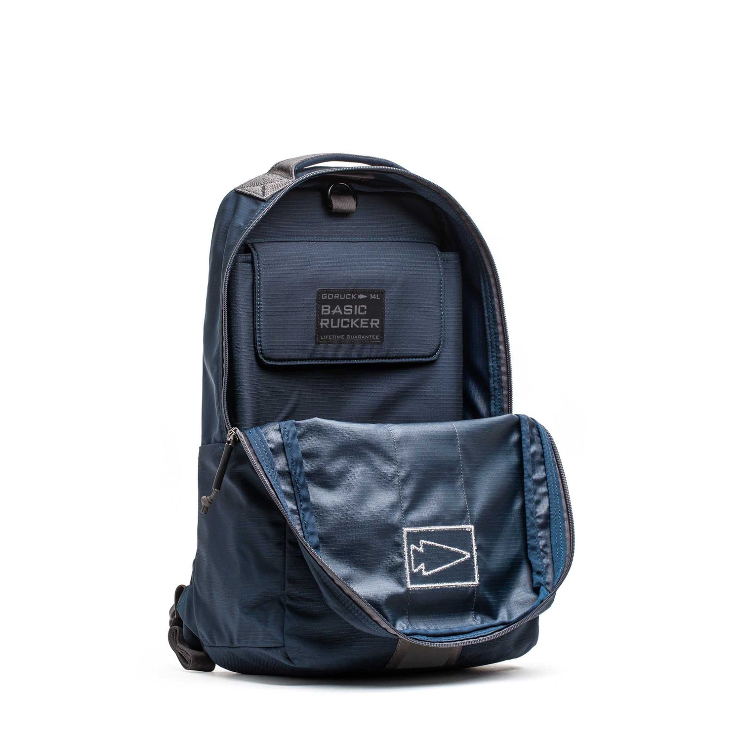 A Basic Rucker stands upright with its front flap open, showcasing inner compartments and a clearly labeled pocket specifically designed to securely hold a ruck plate—ideal for rucking enthusiasts who value both functionality and style.
