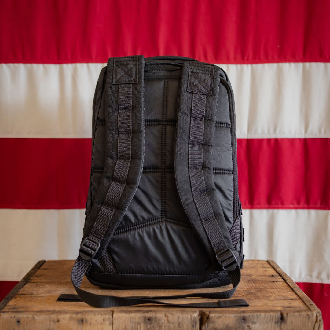 The Join or DIE GR1 21L - Built by Scars sits on a wooden table before a red and white striped flag.